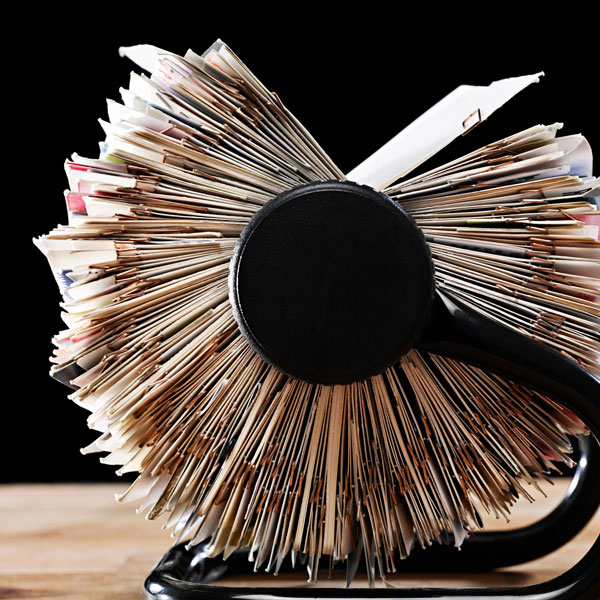 A black Rolodex stand supporting a stack of books, illustrating a combination of reading material and office organization.