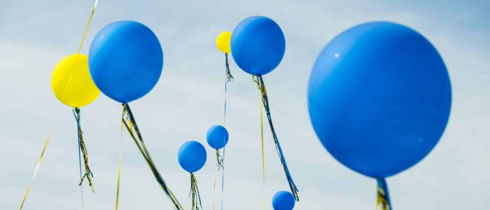 A cluster of blue and yellow balloons floating against a clear sky, creating a vibrant and cheerful atmosphere.